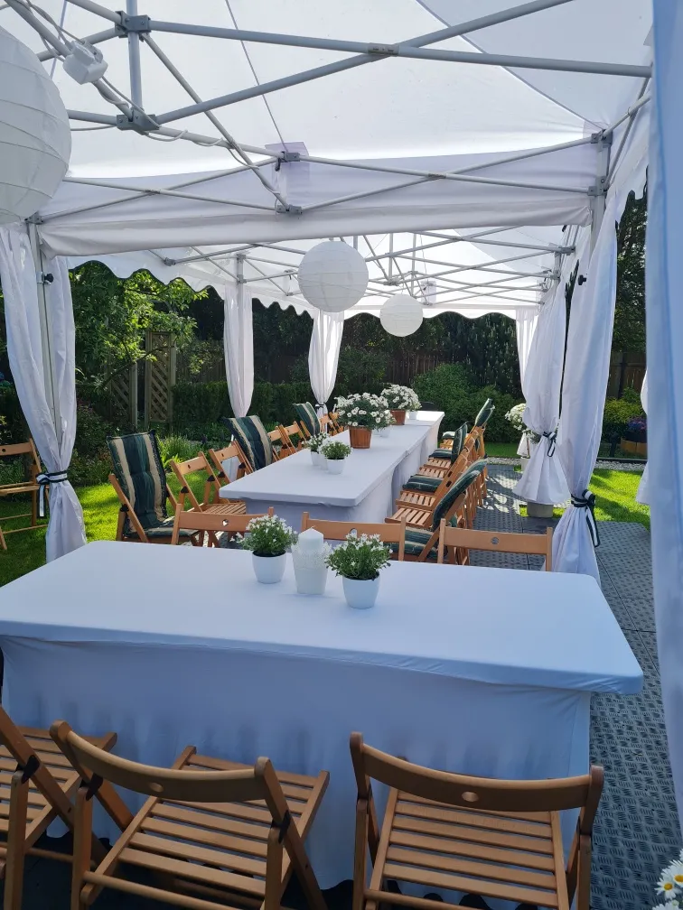Stoły z białymi obrusami pod namiotami